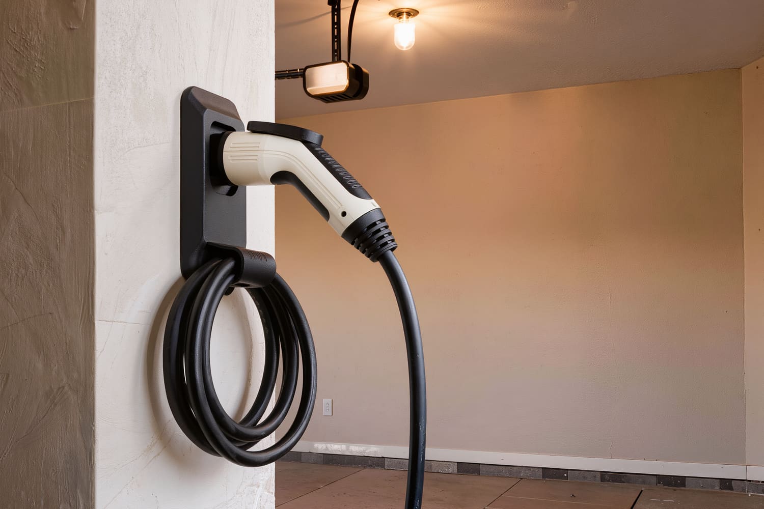 Close view of a charging connector seated in its wall holster with the cable coiled beneath it