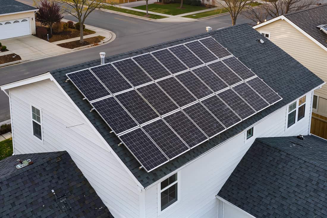 Flush-mounted solar array set square across the asphalt shingle roof slope of a suburban house