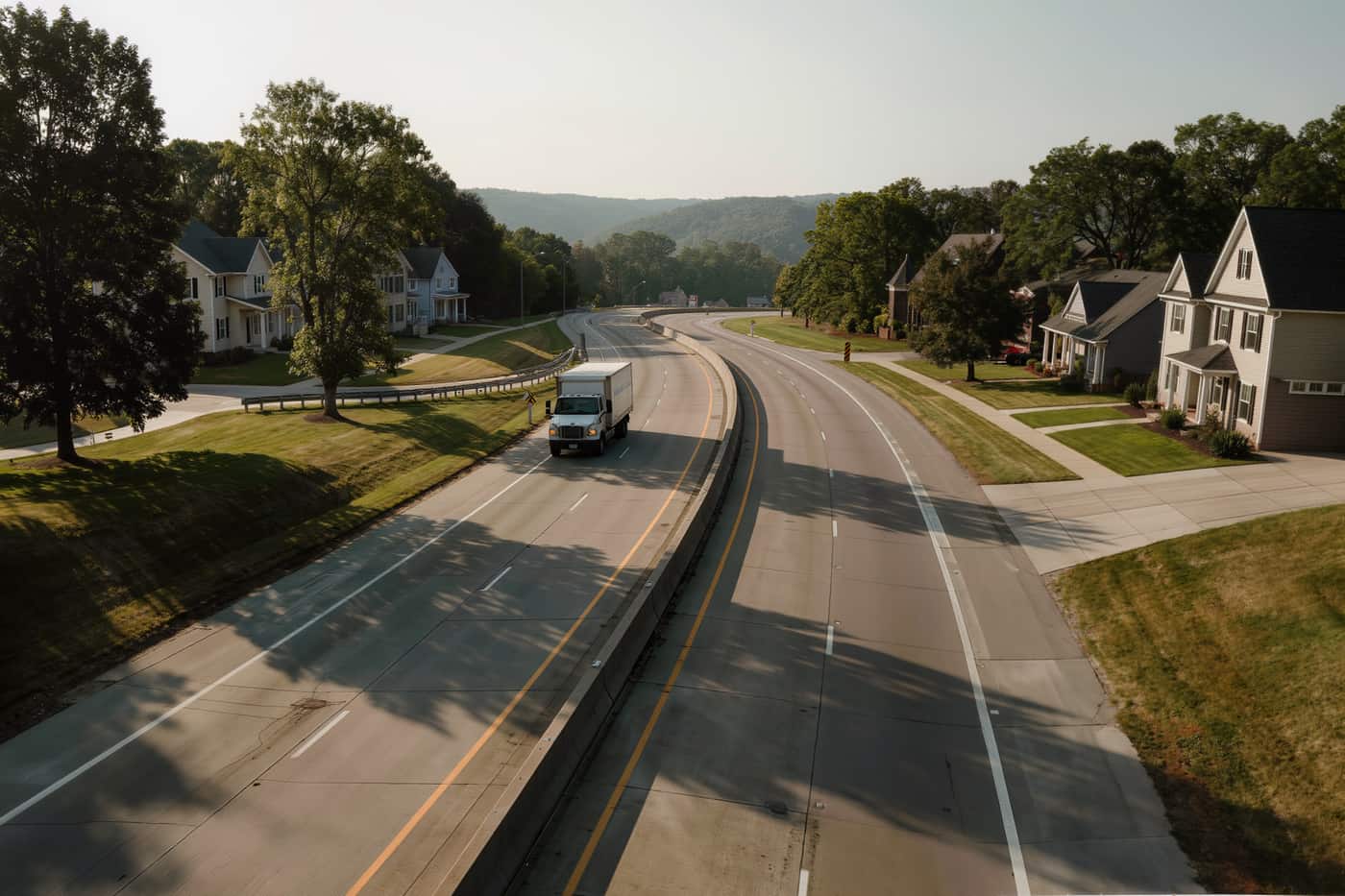 Unmarked truck seen small and far off on a long curve of interstate through rolling country