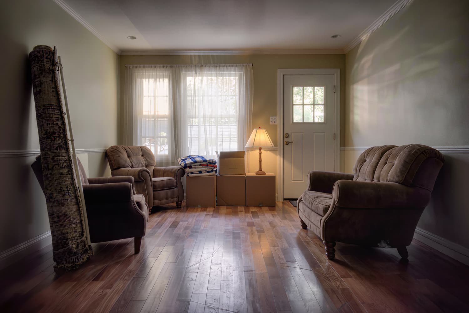 Living room at the end of a move with furniture placed and folded blankets squared by the wall