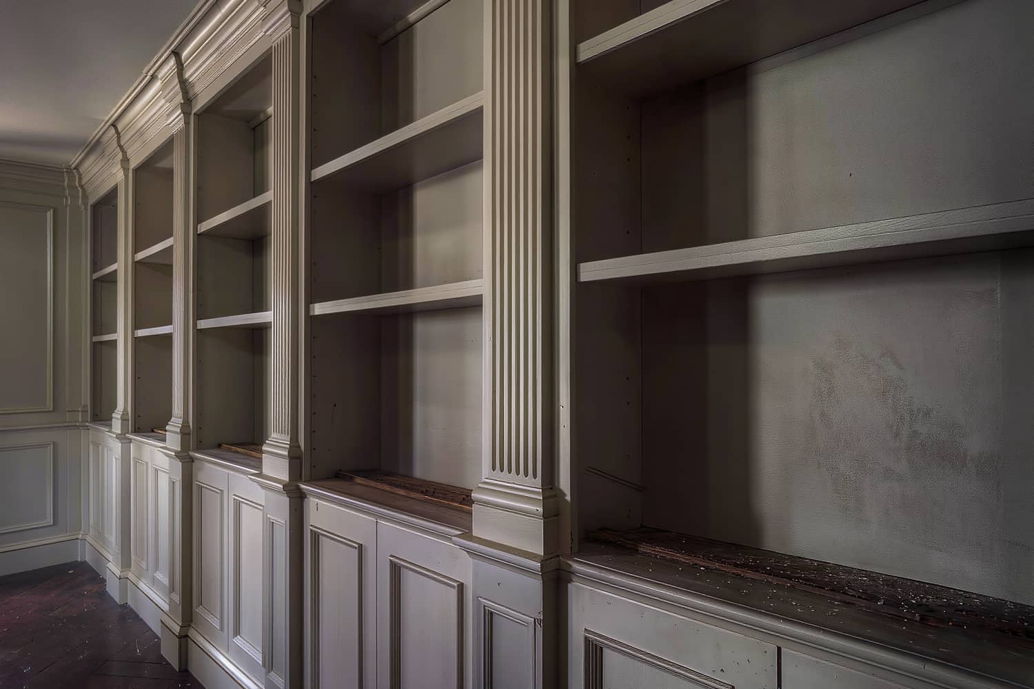 Raking close view of painted panelled millwork with fluted pilasters and bare integrated shelves