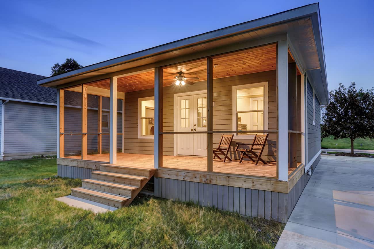 Screened porch on the rear of a house glowing warm from within at dusk