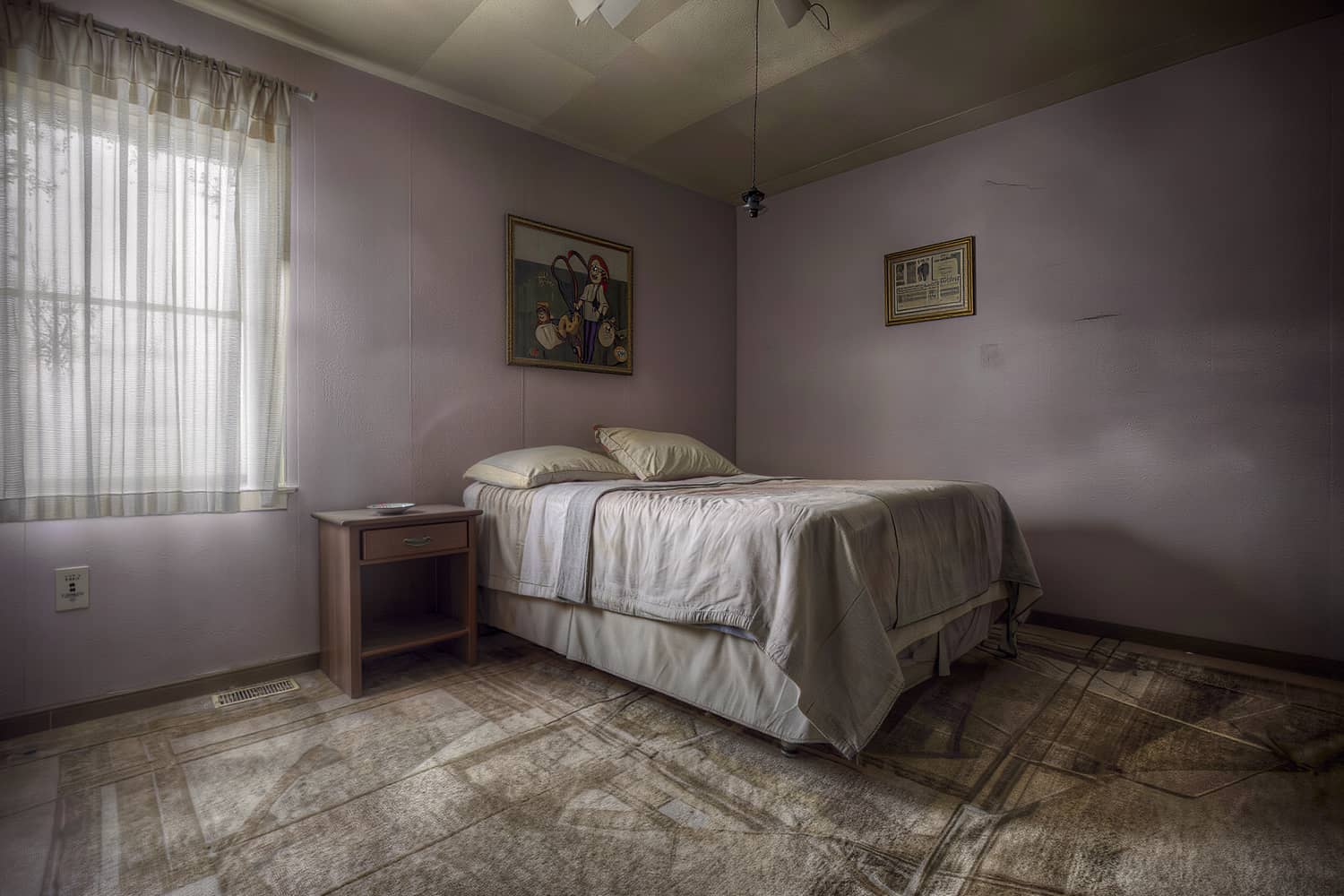 Made bed with squared linen pillows and a bare dusted nightstand in a cleaned bedroom