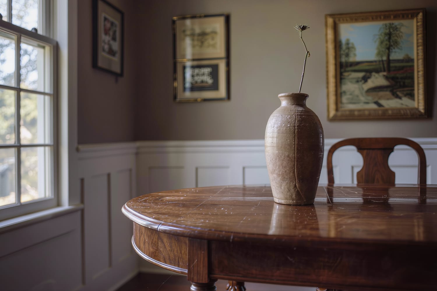 Close still life of a polished walnut dining table corner with a single stem in a plain vase