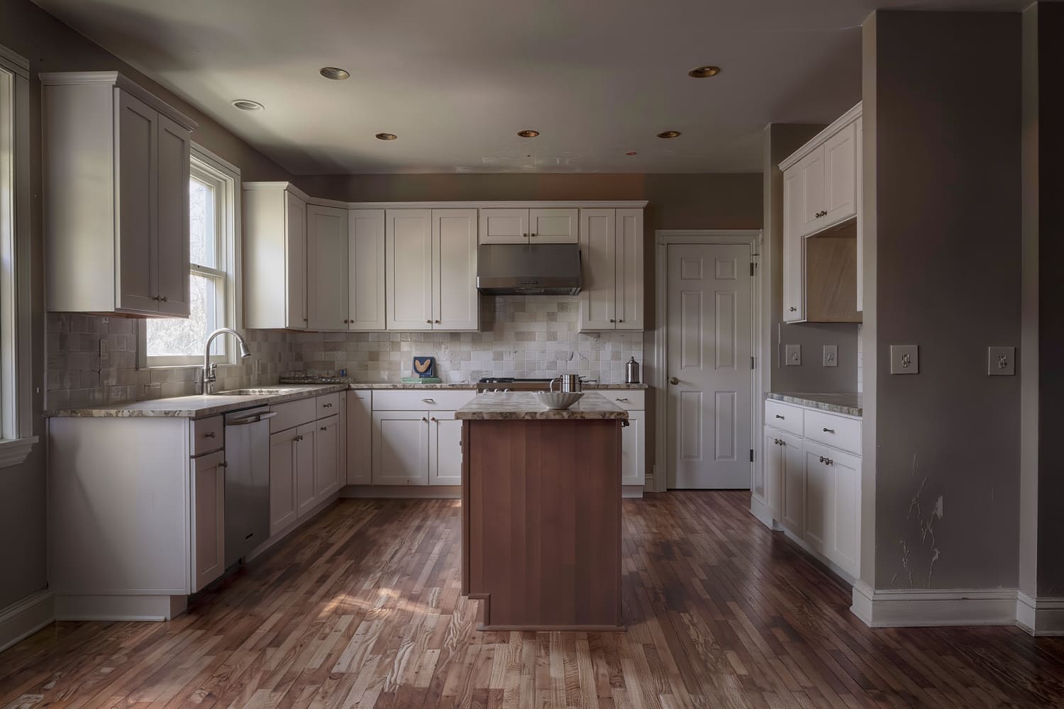 Wide view of a cleared kitchen island and polished range hood at sunrise