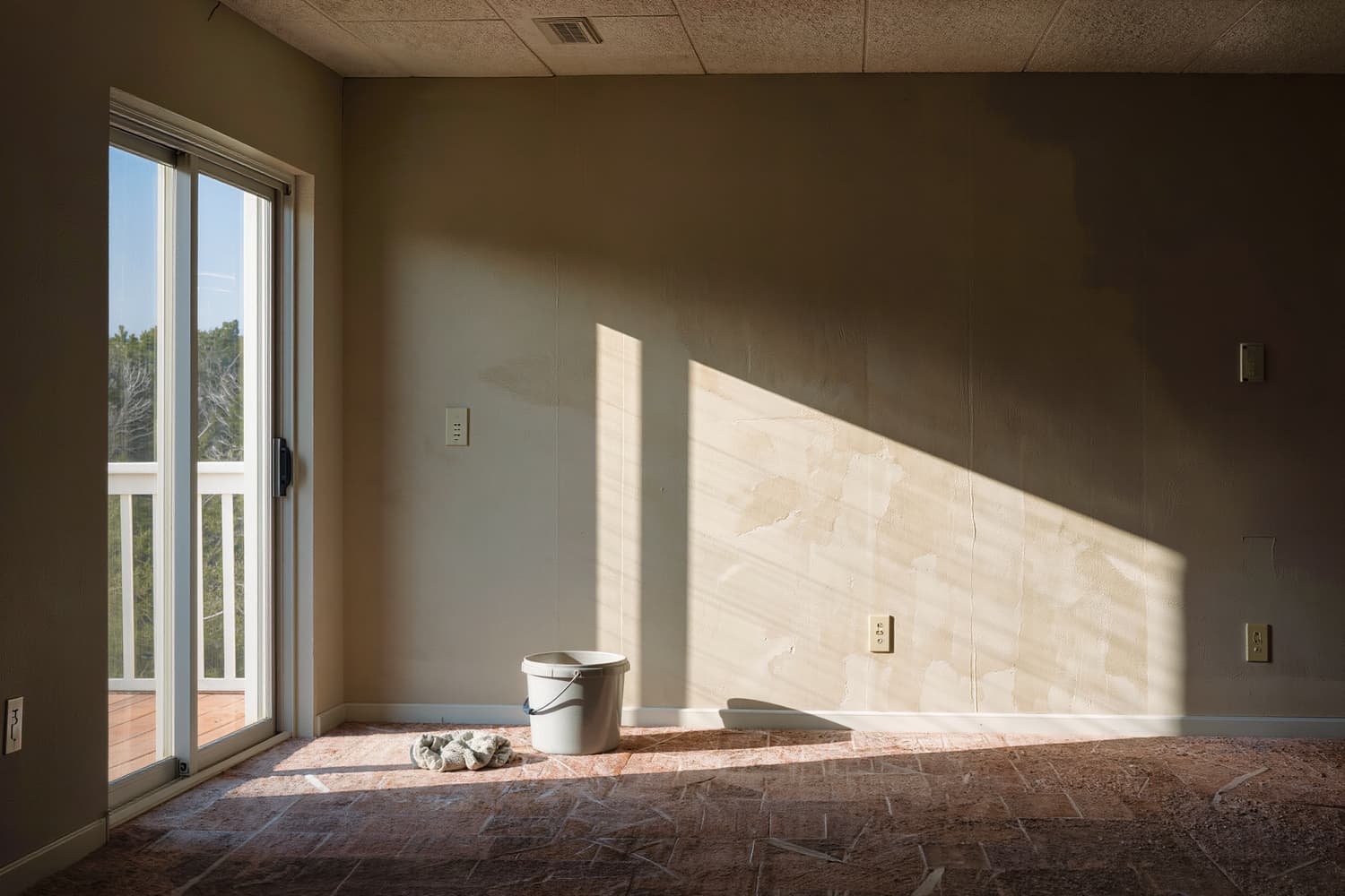 Cleaner seen from behind drawing a squeegee down a tall sliding glass door