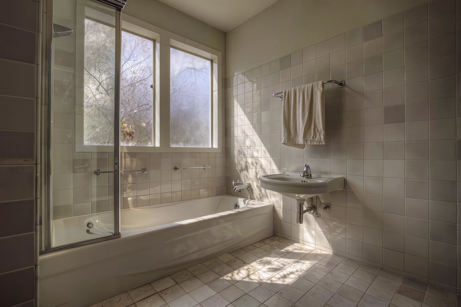 Wide view of a cleaned bathroom with an alcove tub and towels squared on a rail