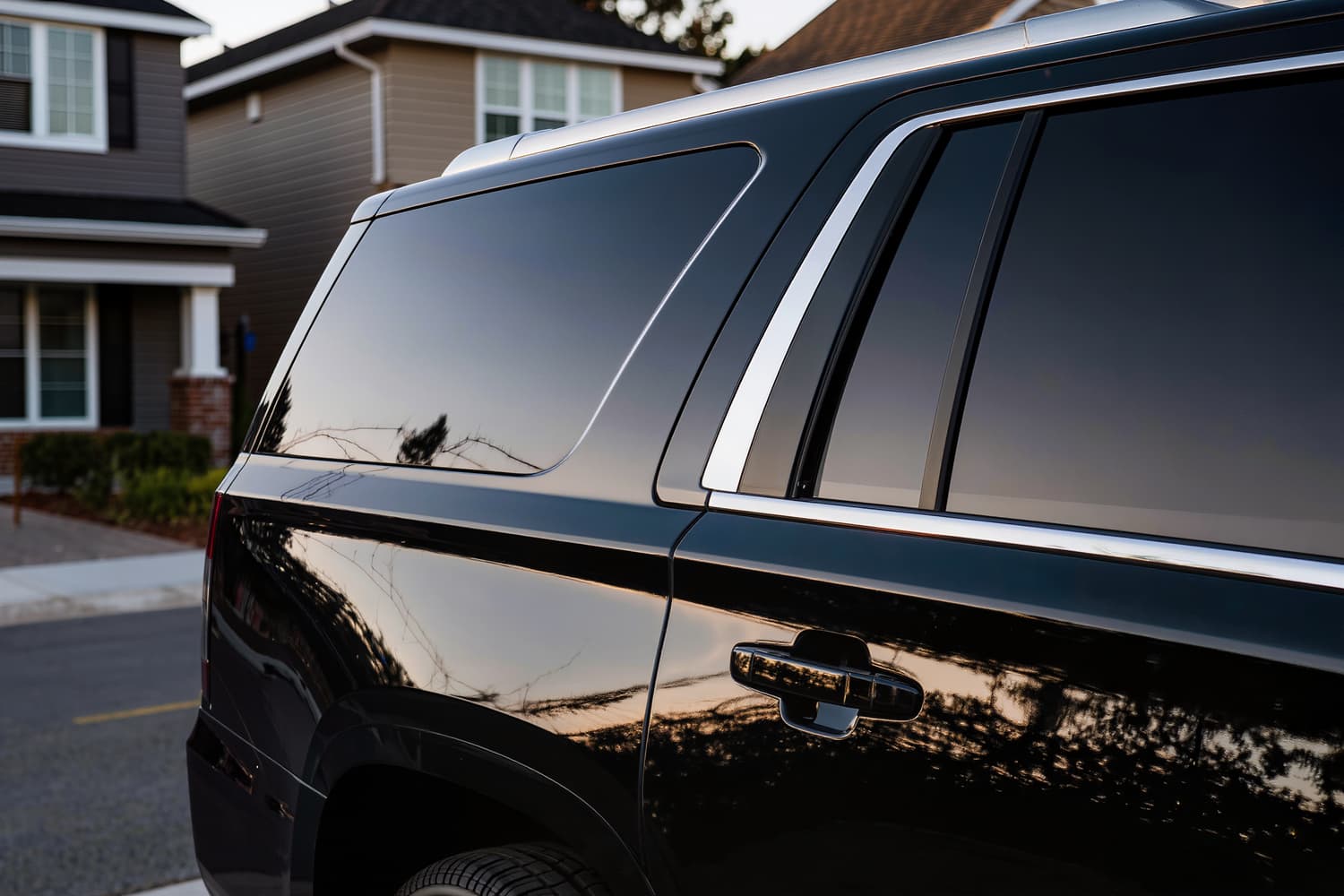 Tree line reflected in the mirror finish of a polished black SUV door