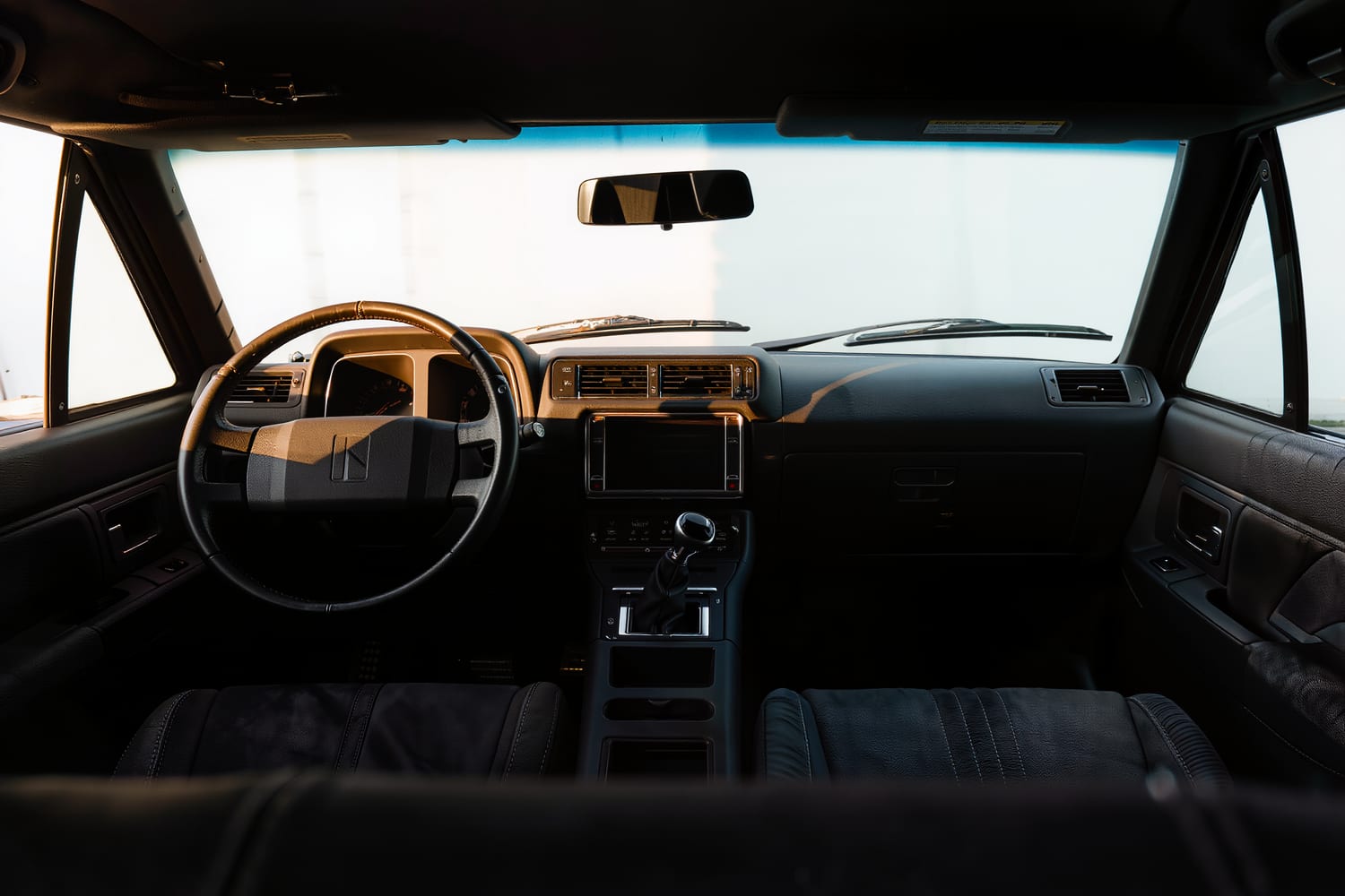 Cleaned dashboard and console in a car cabin lit by low warm sunlight