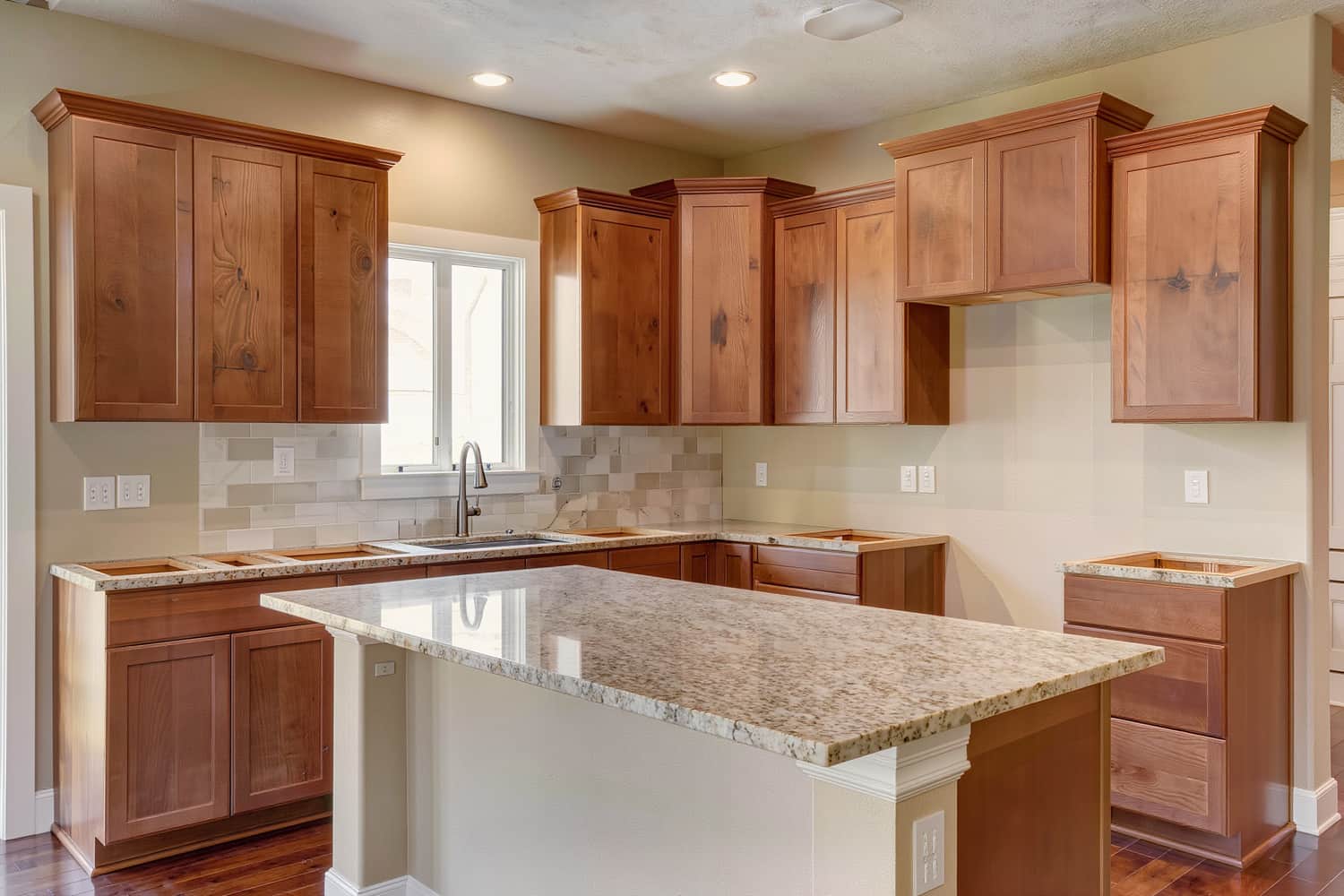 Finished kitchen remodel with a long island, shaker cabinets and a plain tile backsplash