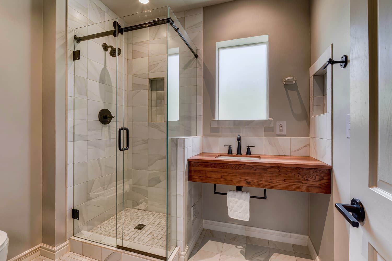 Finished primary bathroom with a curbless tiled shower, frameless glass and a floating vanity