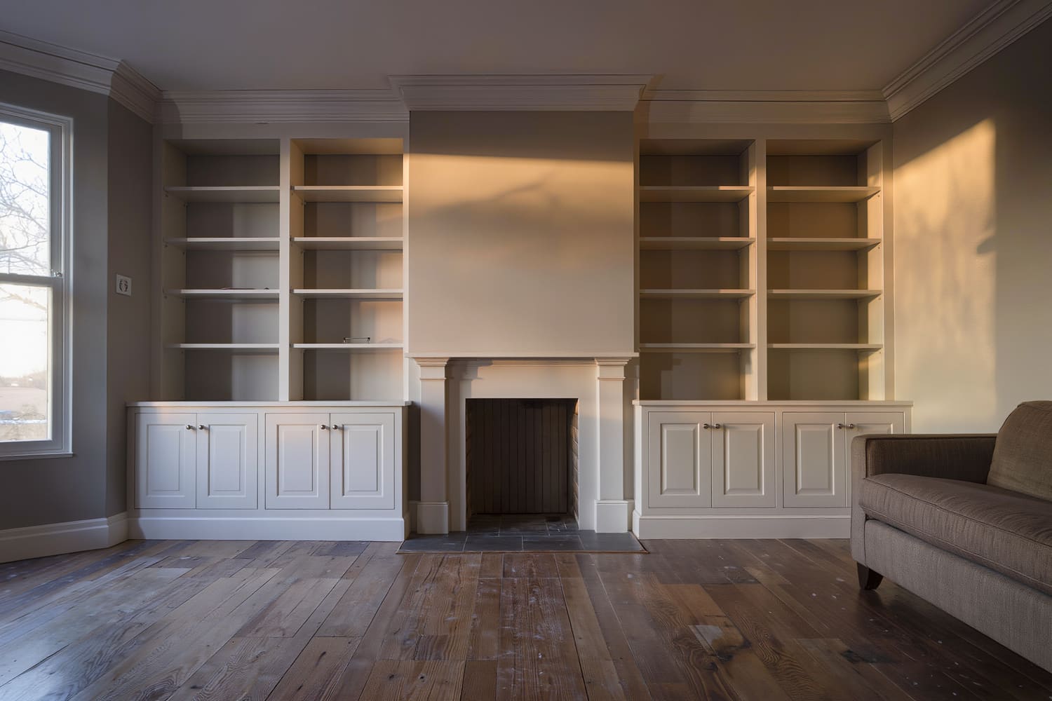 Living room with new painted floor-to-ceiling built-ins flanking a plain plaster fireplace