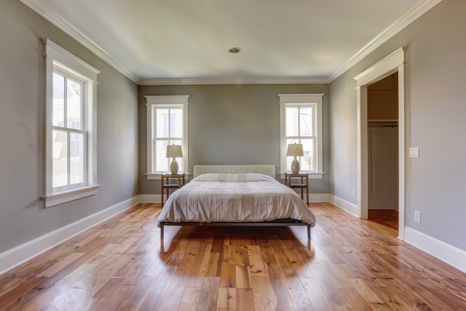 Remodelled primary bedroom with new trim, wide-plank oak floor and plain linen bedding