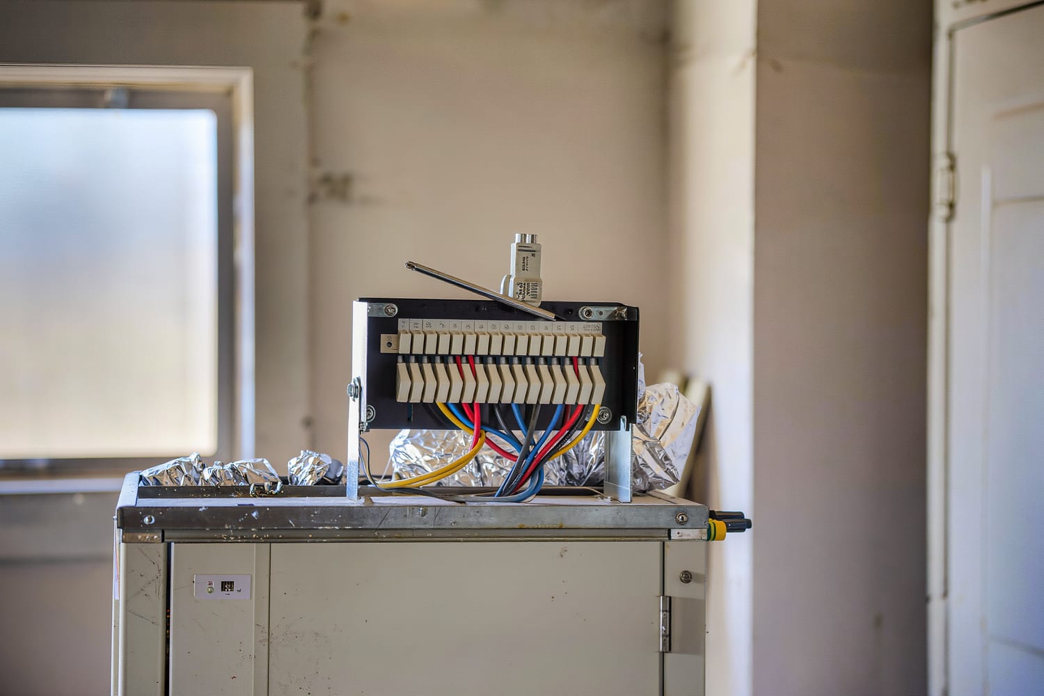 Close view inside an air handler cabinet of a control board with thermostat wires landed on terminals