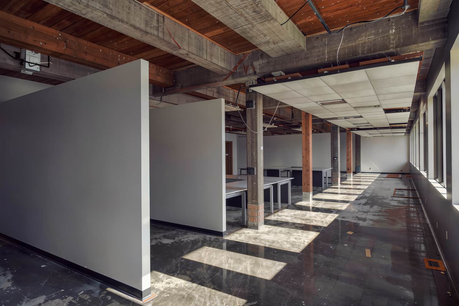 A finished office floor with exposed structure, new ceiling grid and bare desks.