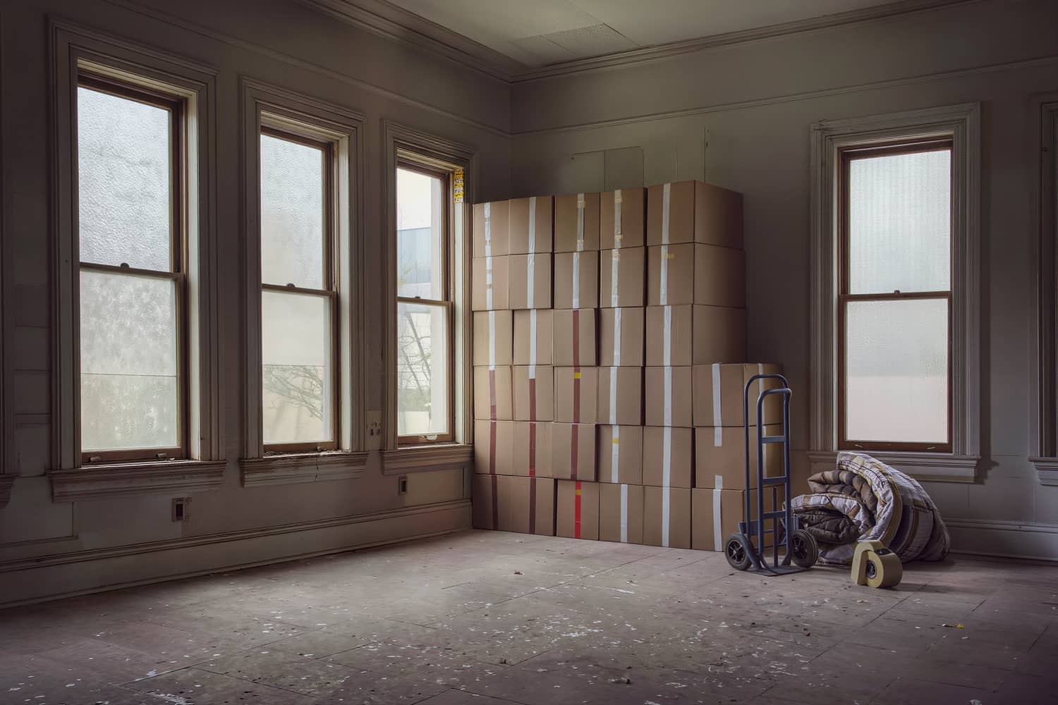 Plain cardboard cartons stacked in even tiers with coloured tape bands as room codes.