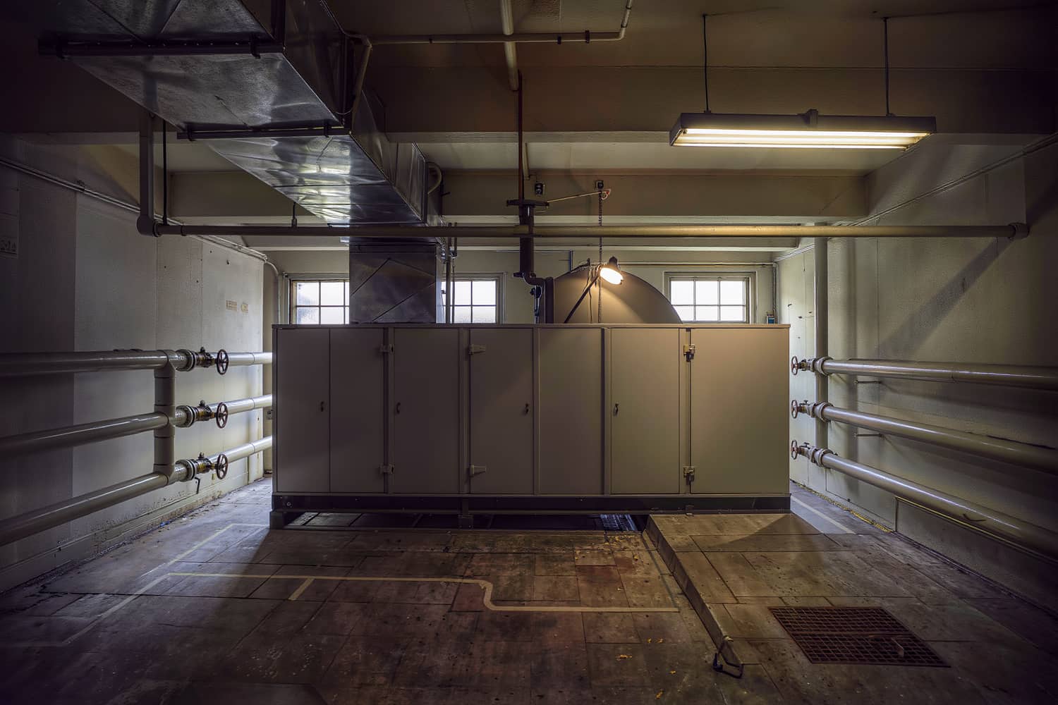 A commercial mechanical room with a floor-mounted air handler and insulated ductwork