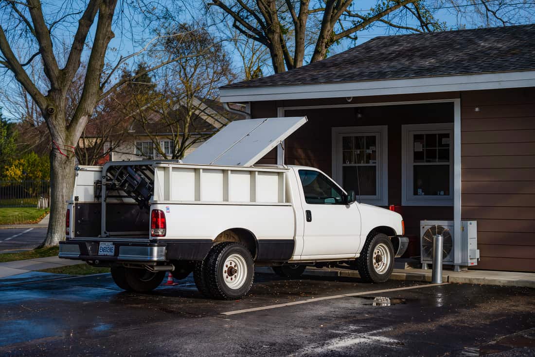 A service pickup backed up to the rear service door of a low commercial building at dawn