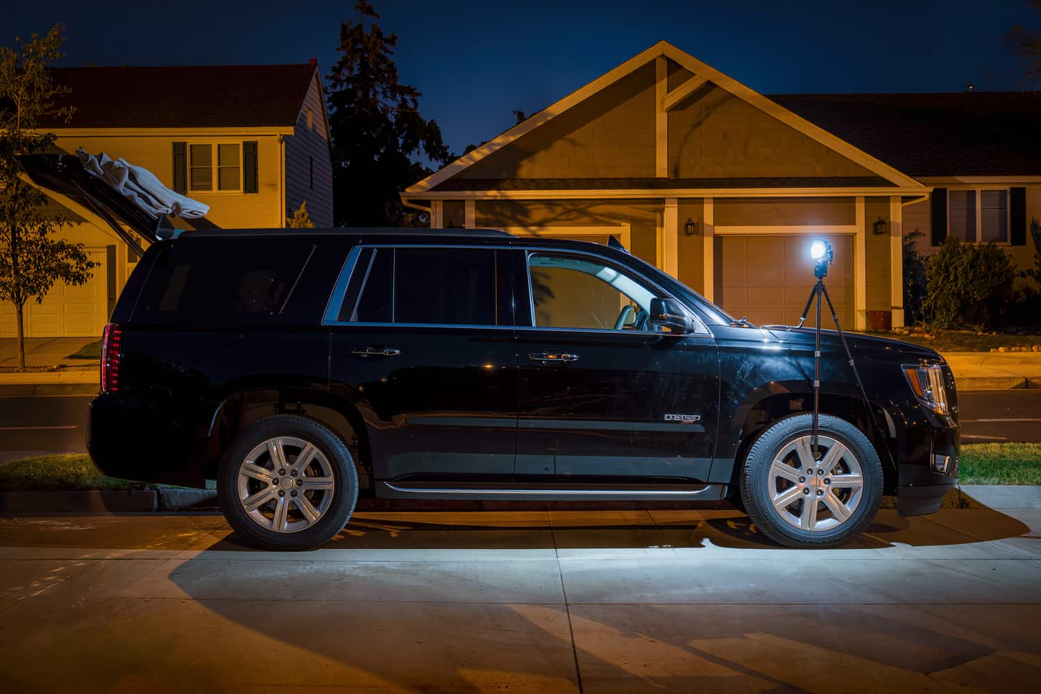 Black SUV on a driveway after dark, polished to a mirror finish under a work light