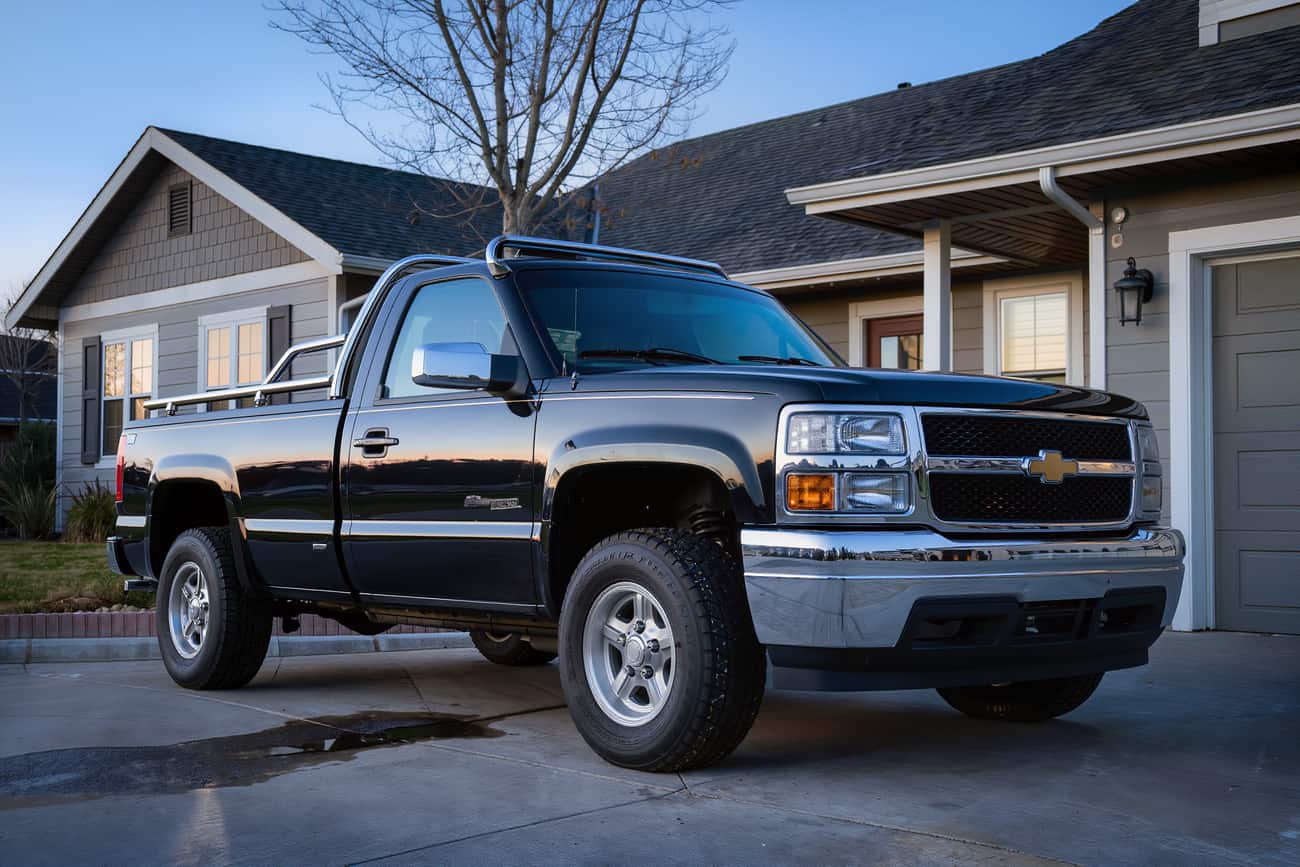 Crew-cab pickup in a suburban driveway at blue hour after a full exterior detail
