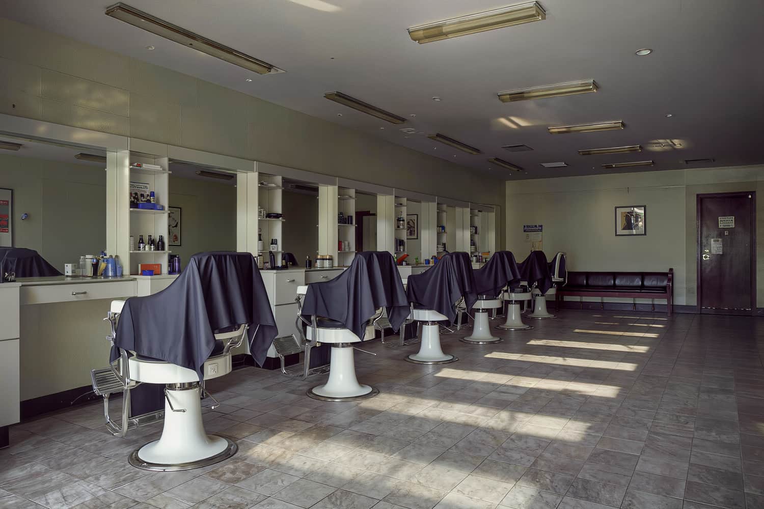 Empty shop floor mid-afternoon, eight chairs in a line under cool daylight