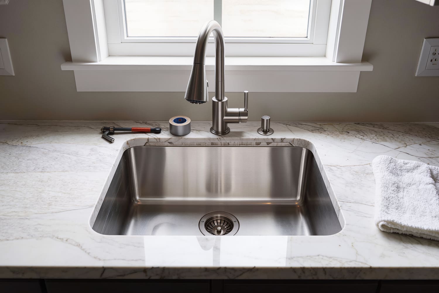 Top-down view of a new undermount sink and pull-down faucet set into a quartz countertop
