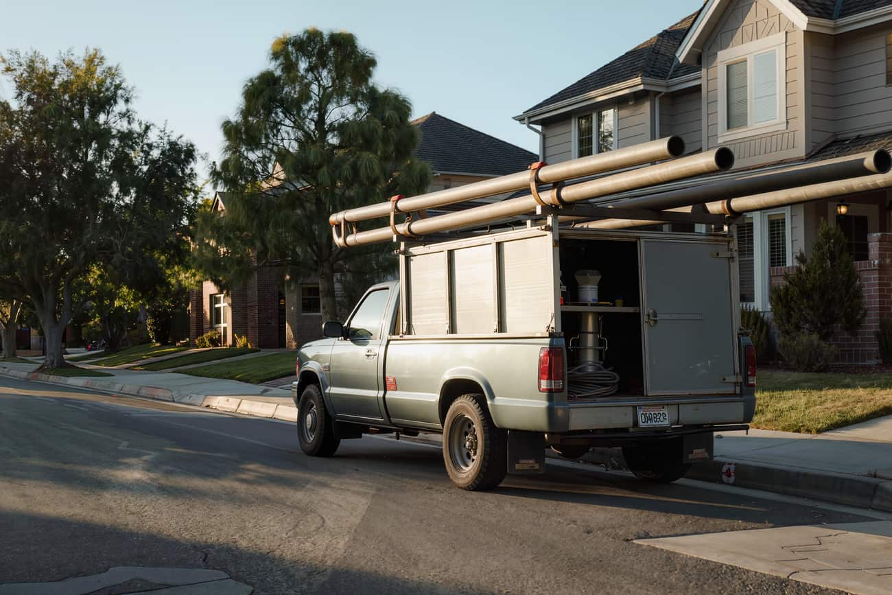 Work pickup with a utility body and pipe rack parked at the kerb of a residential street