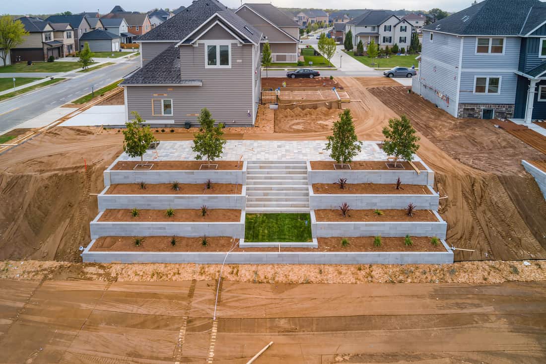 Elevated wide view of a finished sloped lot with board-formed concrete planter walls