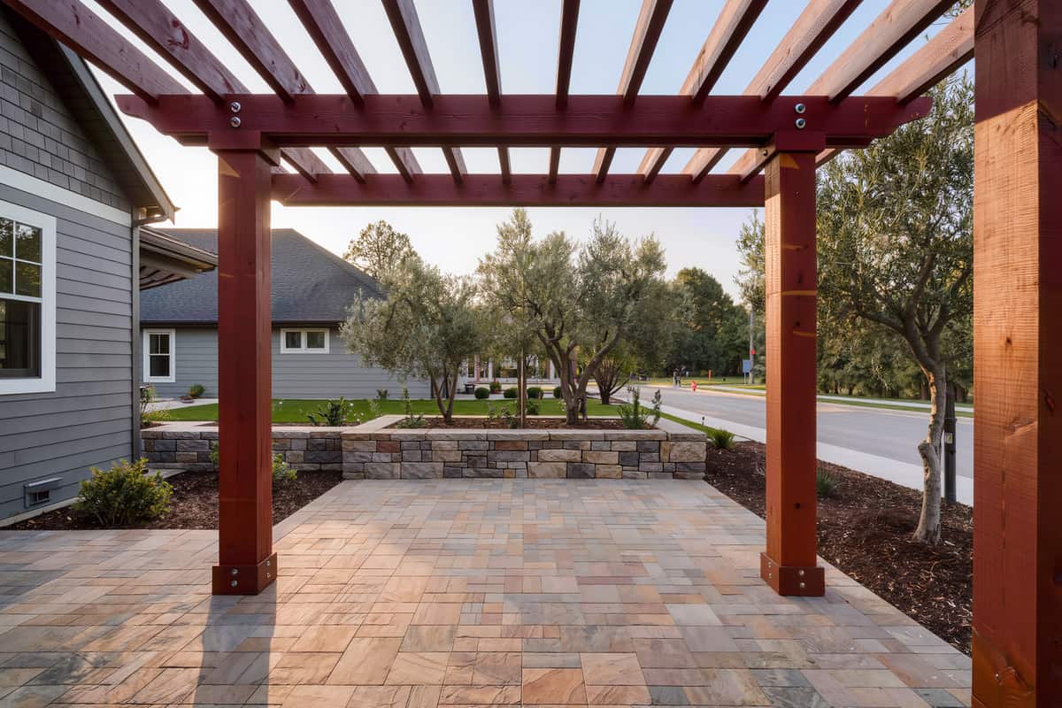 Wide view of a finished back garden with paver terrace, pergola and stone seat wall