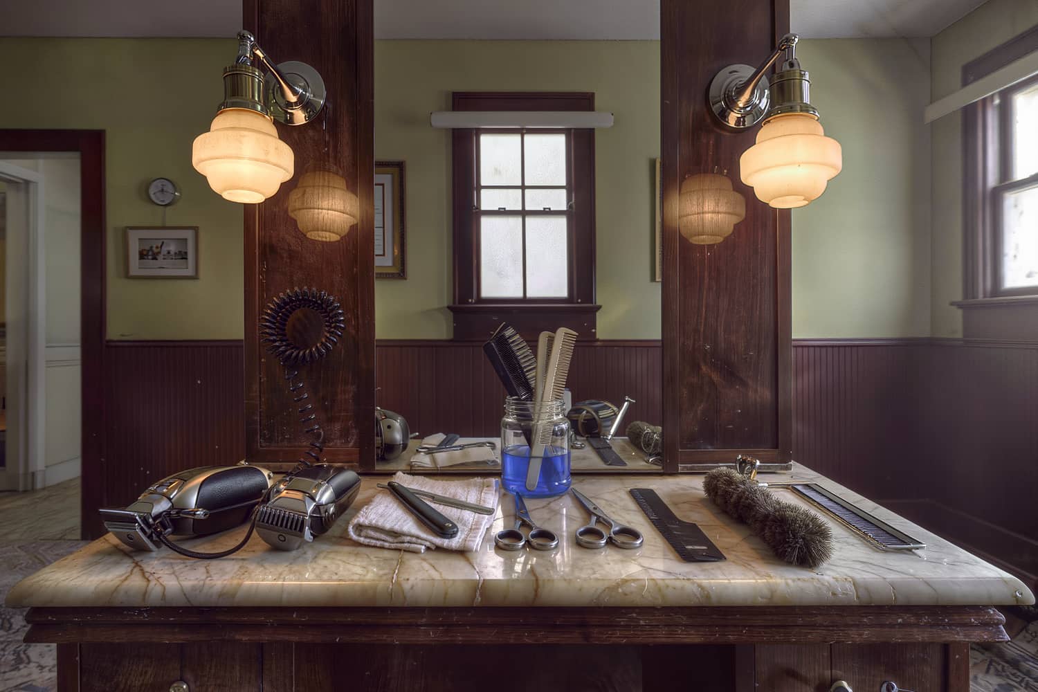 Near-overhead view of clippers, shears and a straight razor laid out on a marble station