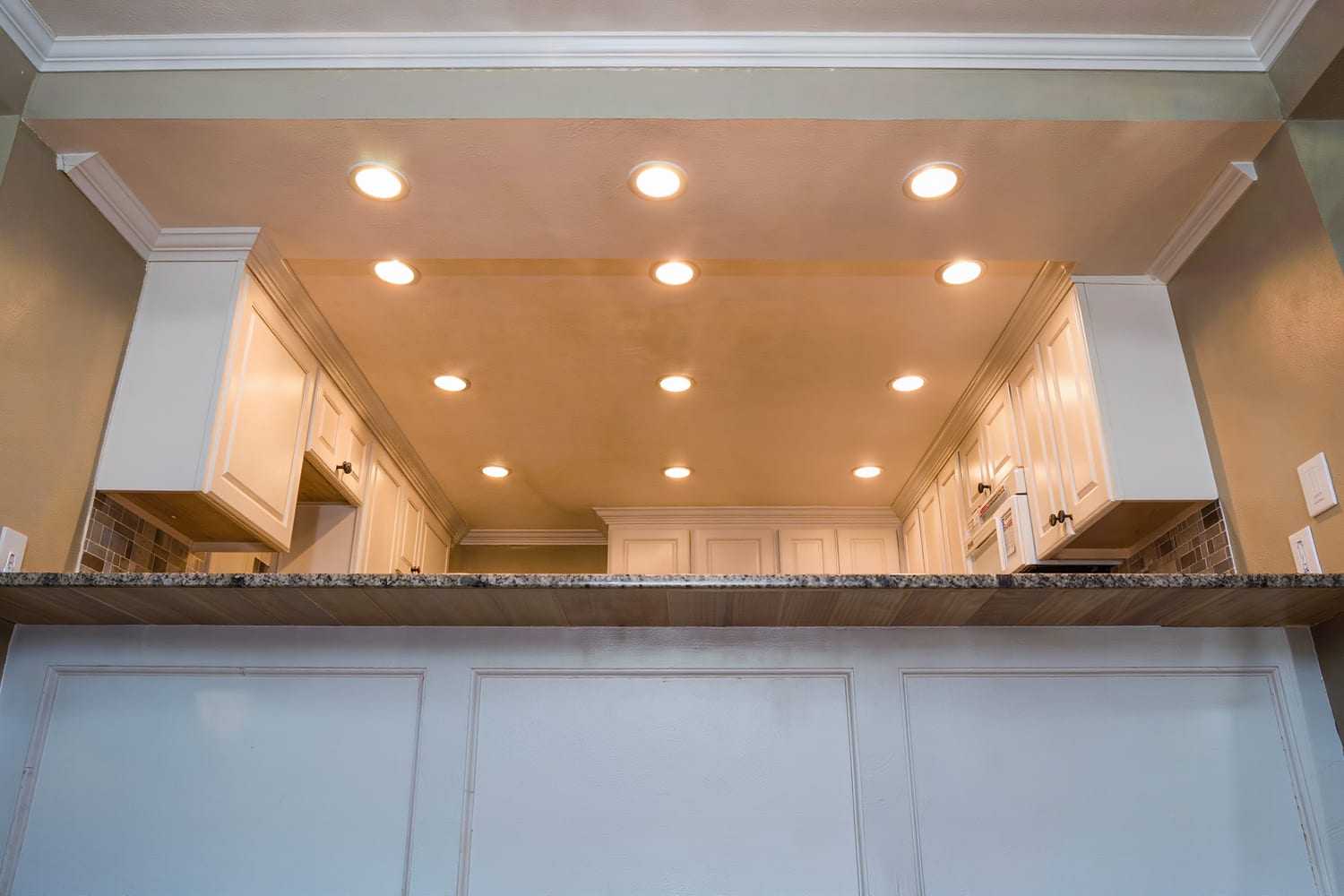 Run of recessed downlights washing across a modern kitchen ceiling and island
