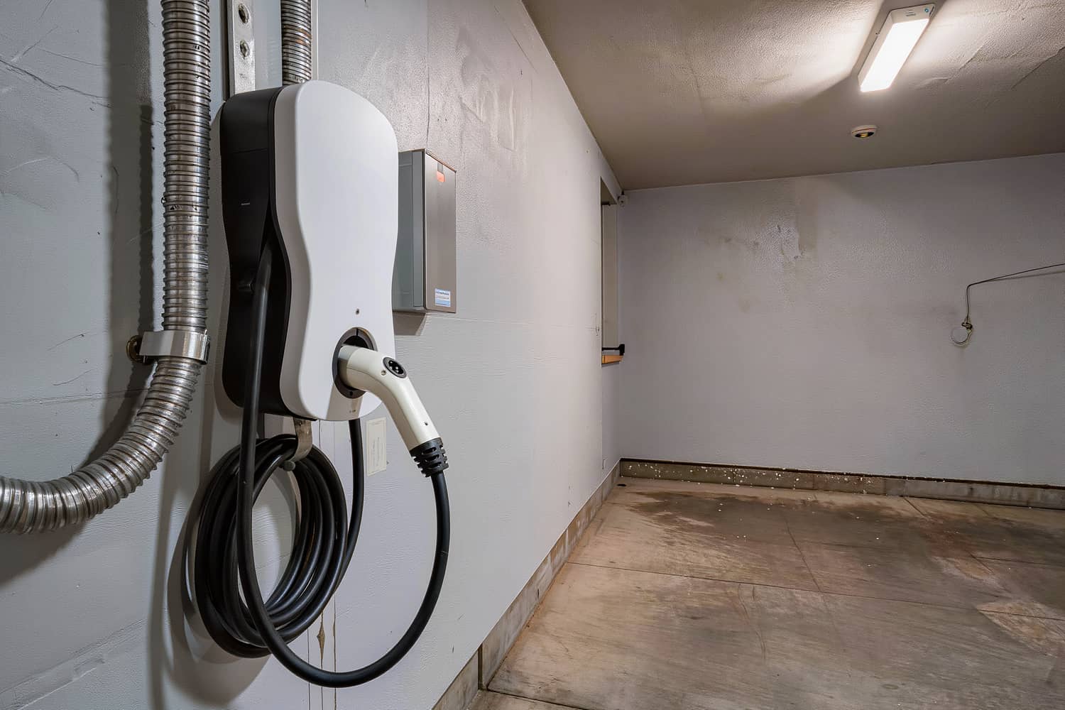 Night detail of a garage vehicle charger with the connector docked in its holster