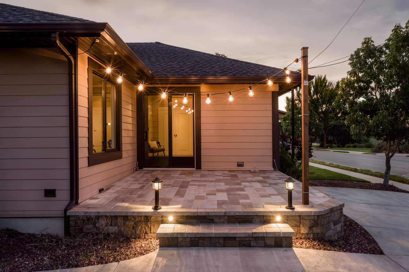 Paver patio at dusk with step lights, path lights and a run of cafe bulbs on