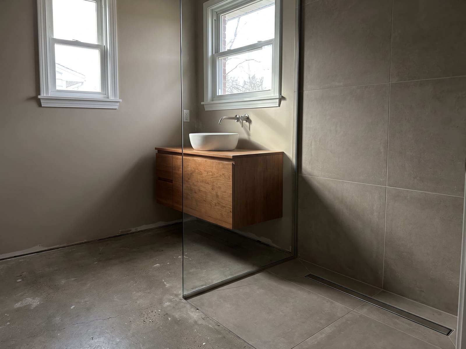 Completed bathroom with a curbless tile shower and a floating vanity