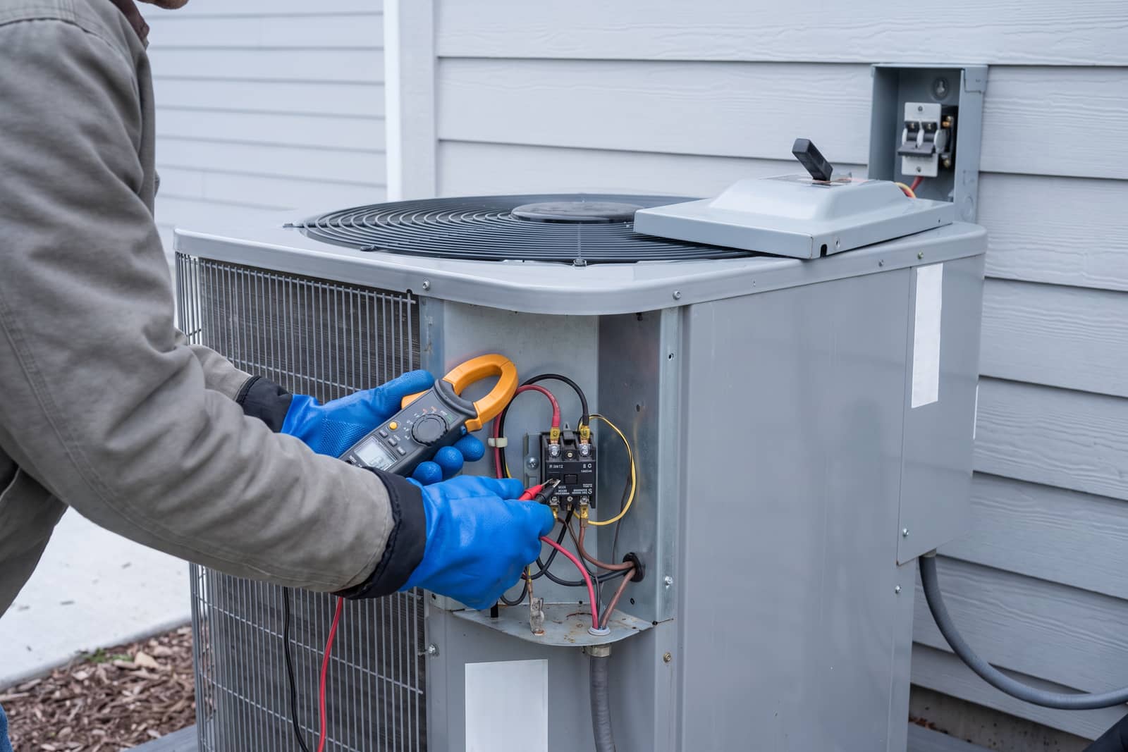 Clamp meter on a condenser's contactor with the disconnect pulled and insulated gloves on